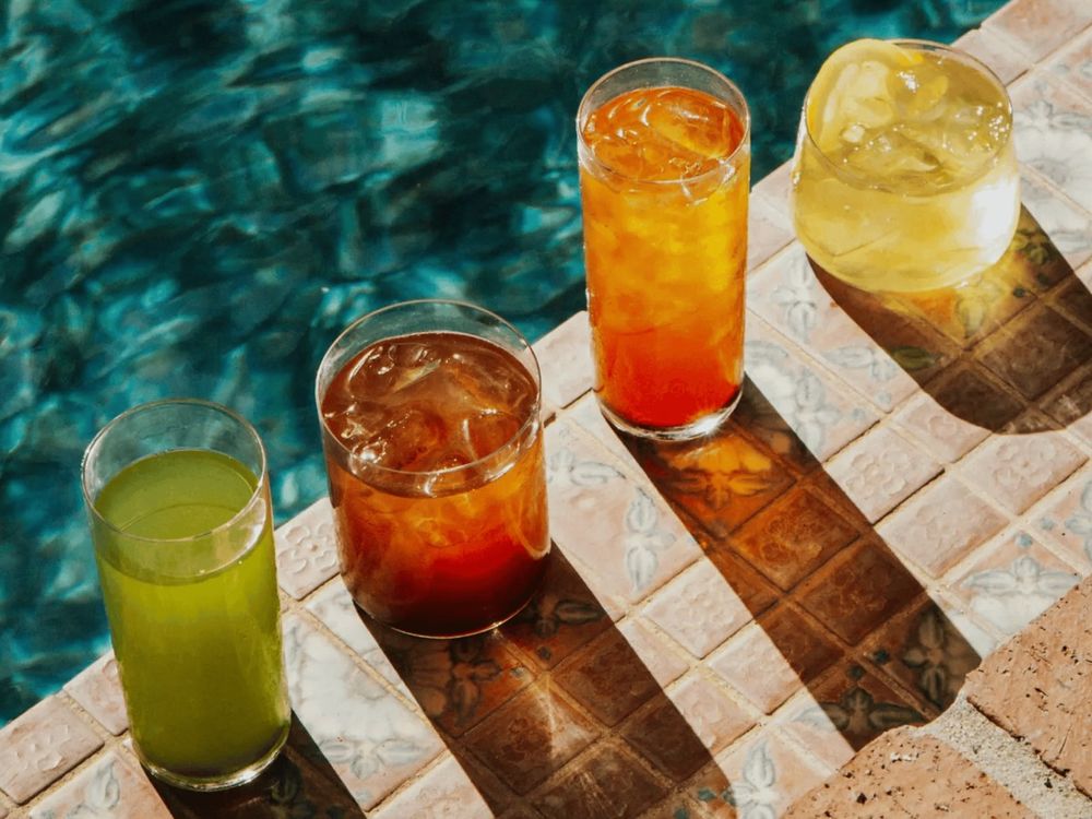 Iced Pique teas on a poolside ledge in sunlight